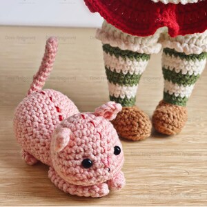 May include: A pink crocheted amigurumi kitty with black eyes, lying on a wooden surface. The kitty is part of a vintage fruits collection. The text "Fruit Kitty" is written in cursive at the top of the image.