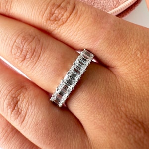 May include: A silver band ring with a row of emerald-cut diamonds.
