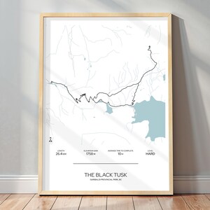 May include: Framed print of a map with a trail route, elevation gain, and time to complete. The map features a black trail line, light blue water features, and the text "THE BLACK TUSK" and "GARIBALDI PROVINCIAL PARK, BC". The length is 26.4 km, elevation gain is 1758 m, and average time to complete is 10 hours.