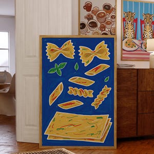 Pode incluir: Uma impressão artística emoldurada com várias formas de massa em amarelo e vermelho sobre um fundo azul. A obra de arte inclui laços, penne e fusilli, juntamente com folhas de manjericão. Outras impressões artísticas emolduradas são visíveis no fundo.