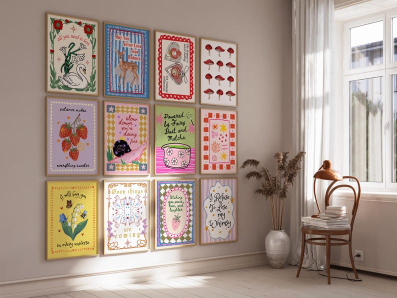 May include: A gallery wall featuring twelve rectangular framed art prints with various illustrations including a swan, a deer, mushrooms, strawberries, a snail, a matcha bowl, and floral motifs, each containing unique handwritten text in colorful designs.