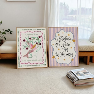 May include: Two rectangular framed wall art prints. The left print features a mermaid illustration with the text A daughter of the sea, made of seafoam and a little mischief. The right print has purple stripes and the text I Refuse To Lose my Whimsy.