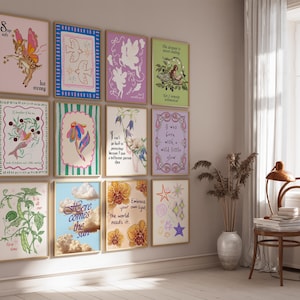 May include: A gallery wall featuring twelve rectangular framed art prints with various illustrations and text, including phrases like Stay soft but strong, Here comes the sun, and Embrace your own light, the world needs it, displayed in a grid arrangement.