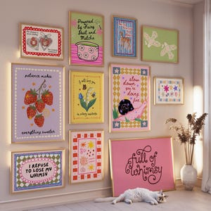 May include: A gallery wall featuring eleven framed art prints with various illustrations and text, including phrases like 'Powered by Fairy Dust and Matcha', 'patience makes everything sweeter', 'slow down you're doing fine', and 'full of whimsy'.