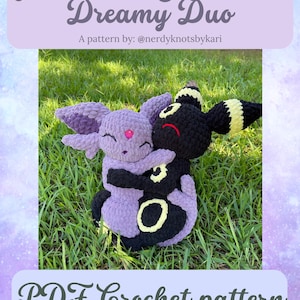 May include: A crochet pattern featuring two plush figures, one lavender and one black, embracing on a grassy surface. The lavender figure has pink accents, while the black figure has yellow details. Text reads "Moonbeam & Shadow Dreamy Duo" and "PDF Crochet pattern".