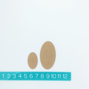 May include: Two brown cardboard circles, one larger than the other, on a white background with a blue ruler marked with numbers 1 through 12.