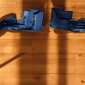 Könnte beinhalten: Zwei blaue Kunststoff-Kotflügelverkleidungen. Die Verkleidungen sind gebogen und haben eine strukturierte Oberfläche.