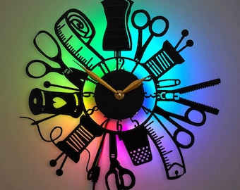 May include: A colorful clock with a rainbow background and a black silhouette of sewing tools, including scissors, a measuring tape, and a spool of thread. The clock face is black with white numbers and gold hands.