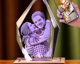 Puede incluir: Un prisma de cristal con una foto de pareja grabada en su interior. El prisma está iluminado desde abajo, proyectando un suave brillo sobre la imagen. El texto "My Love Forever" está grabado en la parte inferior del prisma. El prisma está sentado sobre una base de madera.