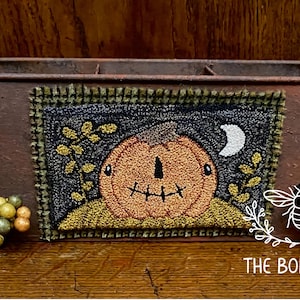 May include: A rustic metal planter with a stitched pumpkin design. The pumpkin is orange with a stitched face, set against a dark background with a crescent moon and foliage. The Bonny Bee logo is visible.