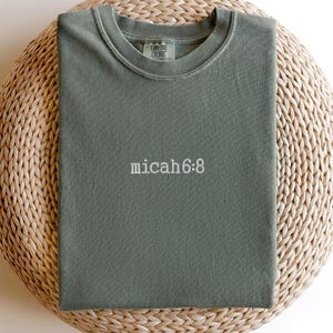 May include: A green t-shirt with the text "COMBAT COLORS" on the tag and the text "micah 6:8" on the front.