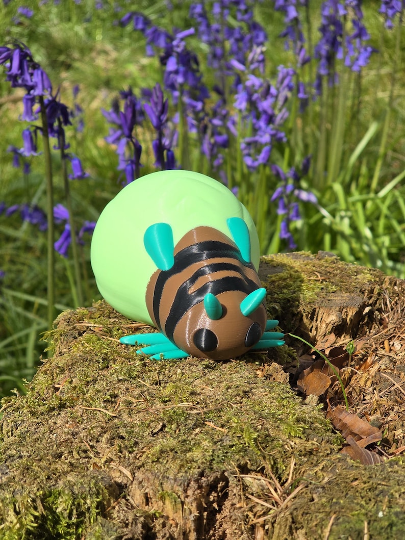 A high-quality hero shot of the 3D printed Palia Lantern Bug figurine resting on a textured, moss-covered tree stump. The vibrant turquoise legs and antennae, brown striped body, and large light-green abdomen pop against the natural forest background. In the soft-focus distance, a field of purple bluebells and green trees creates a magical, "Bahari Bay" atmosphere. This shot perfectly captures the whimsical, game-accurate feel of the collectible in a natural outdoor setting.