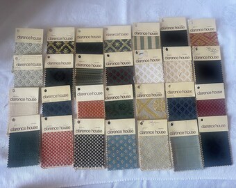 May include: A collection of fabric swatches from Clarence House, a luxury fabric brand. The swatches are arranged in rows and columns on a white surface. The swatches are in various colors and patterns, including stripes, checks, and florals.