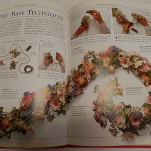 May include: A book page with instructions on how to make a floral garland using a flexible wire base. The image shows a close-up of the wire base with flowers and leaves attached to it. The text on the page reads "Flexible Base Techniques".