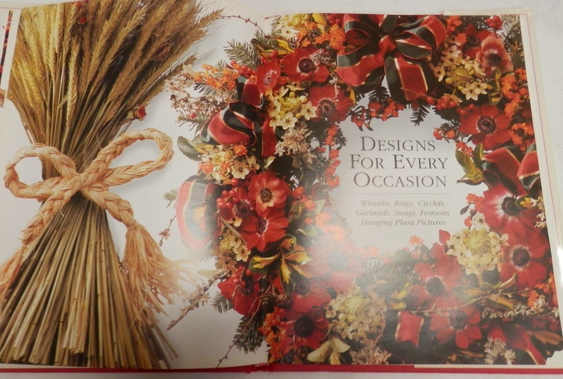 May include: A book titled "Designs for Every Occasion" with a red and green wreath on the cover. The wreath is made of red flowers, green leaves, and red and green ribbon. The book also features a close-up of a bundle of wheat tied with a rope.