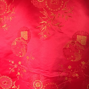 May include: Bright red fabric with gold embroidered circular patterns and floral and bamboo accents. The design includes detailed medallions and stylized botanical elements, creating a rich, textured appearance. The fabric has a slight sheen.
