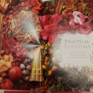 May include: A book titled "Practical Essentials" with a close-up image of various dried flowers, berries, and other natural elements. The book focuses on "Texts and Materials, Plant Ingredients, Step-by-Step Techniques".