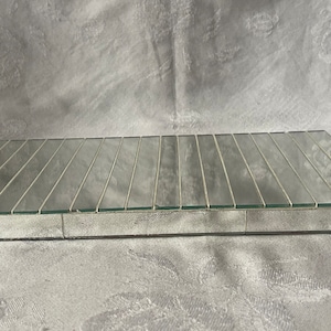 May include: A rectangular mirrored tray with a grid pattern. The tray is made of small, rectangular mirrored tiles, creating a reflective surface. The edges are a neutral color, and the tray is set against a neutral background.