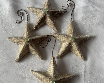 May include: Four handmade paper star ornaments with a green glitter center. Each star has a wire hanger for hanging on a Christmas tree.