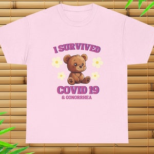 May include: Pink t-shirt with a cartoon bear and the text "I survived COVID 19 & Gonorrhea".