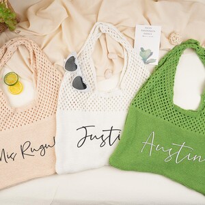 May include: Three crochet tote bags in peach, white, and green. Each bag features a name in cursive script. The peach bag says "Mis Rugu", the white bag says "Justin", and the green bag says "Austin".