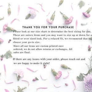 May include: A white informational card featuring scattered pink and purple flower petals and greenery. The text reads: THANK YOU FOR YOUR PURCHASE. Please look at our size chart to determine the best sizing for you. These are unisex items and you may want to size up or down for a fitted or over sized look. For a relaxed fit, we recommend that you choose your go-to size. Since all our items are custom printed once ordered, we do not allow returns or exchanges. All sales are final. If there are any issues with your order, please reach out and we are happy to make it right!