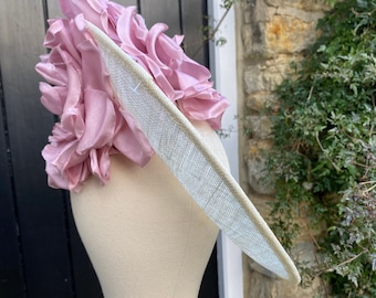 May include: A white hat with a large pink flower on top. The hat is made of straw and has a wide brim.