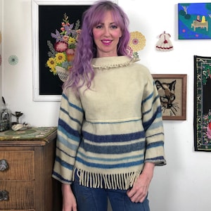 May include: A white ceramic mug with a black handle and the text "But First, Coffee" in a bold, black font. The mug is set against a neutral background, highlighting its simple design.