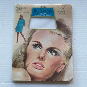May include: Vintage Fruit of the Loom Deluxe sheer stockings in white, size 9 1/2. The packaging features a graphic illustration of a person wearing a blue dress and a large portrait of a person's face. Text includes Seamless Mesh, reinforced heel & toe.