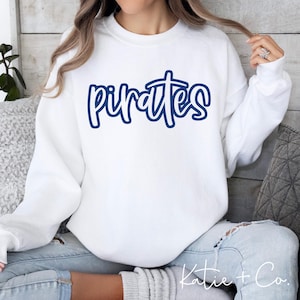 May include: White sweatshirt with the word "Pirates" in a blue script font across the chest. The sweatshirt has long sleeves and a crew neck. The text is outlined in a darker blue.