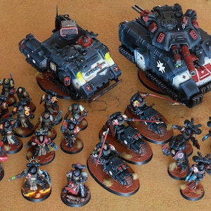 May include: A collection of miniature war game models, featuring two tanks and numerous infantry figures. The tanks are predominantly black with red and white detailing. The infantry figures are in various poses, with detailed armour and weapons.