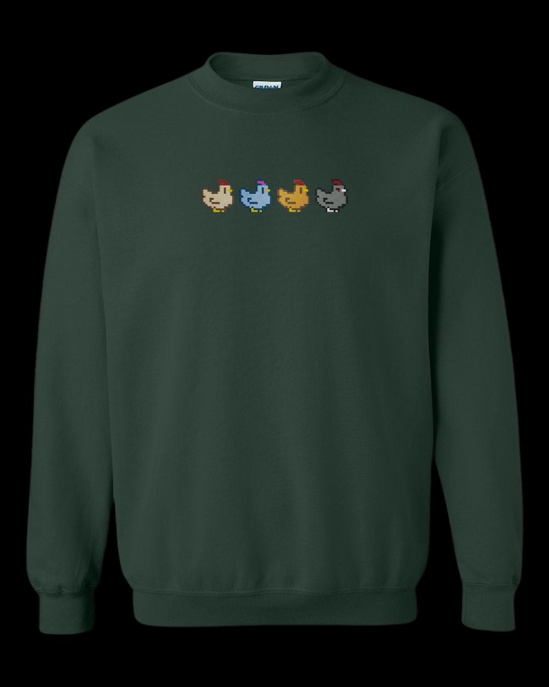 K&ouml;nnte beinhalten: Ein dunkelgr&uuml;ner Pullover mit einem Pixel-Design aus f&uuml;nf H&uuml;hnern in einer Reihe. Die H&uuml;hner sind in verschiedenen Farben: wei&szlig;, blau, gelb, braun und grau.