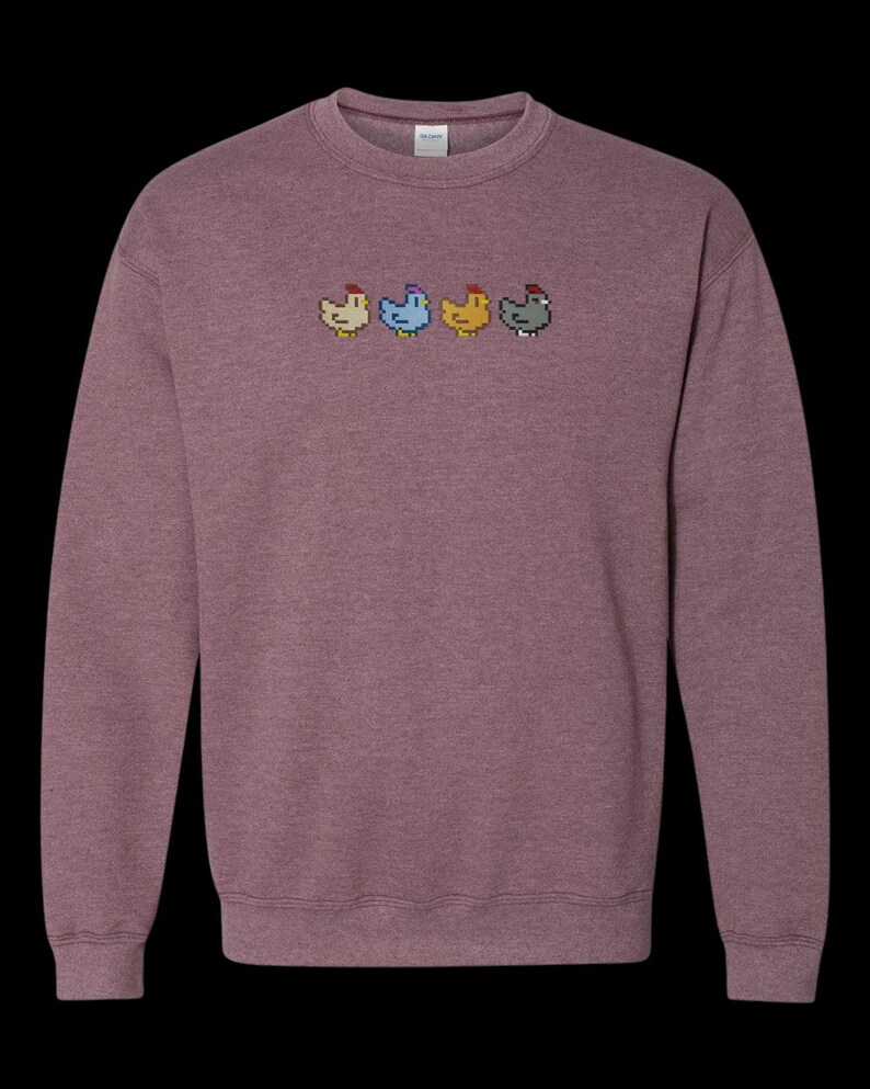 K&ouml;nnte beinhalten: Ein heidefarbenes Sweatshirt mit einem pixeligen Design von vier H&uuml;hnern in einer Reihe. Die H&uuml;hner sind in verschiedenen Farben: rot, blau, gelb und grau.
