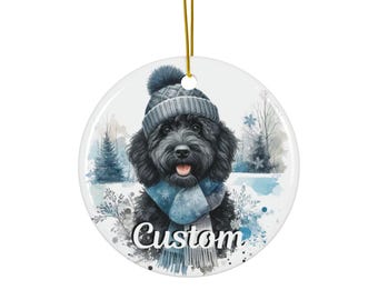 May include: Round ceramic ornament featuring a black dog wearing a gray knit hat and scarf, set against a winter scene with snowflakes and trees. The word "Custom" is written in a script font on the ornament.