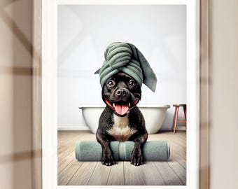 May include: A black dog with a green towel on its head sits on a bath mat in a bathroom. The dog is smiling and has its tongue sticking out. There is a white bathtub and a small stool in the background.
