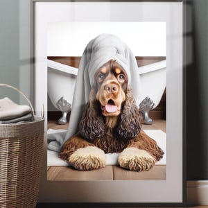 May include: Framed print of a brown and tan Cocker Spaniel with a white towel on its head, sitting in front of a claw-foot bathtub. The dog has a surprised expression, with its tongue sticking out.