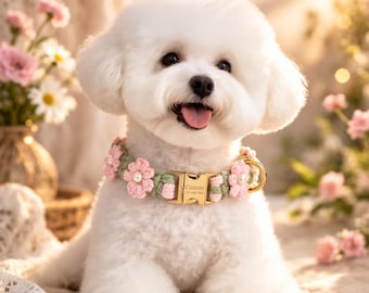 May include: A fluffy white dog wearing a custom-made collar. The collar is green and pink, adorned with pink flower accents. The gold buckle has the word "Custom" and a phone number. The dog is sitting with its tongue out.
