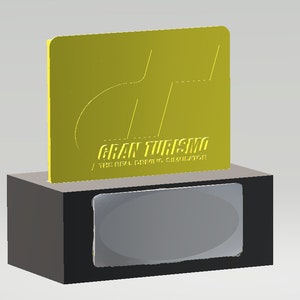 May include: A gold trophy with a black base. The trophy features a stylized "GT" logo and the text "Gran Turismo / The Real Driving Simulator".