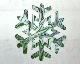 May include: A green and white marbled snowflake ornament. The snowflake is cut out of paper and has a swirling pattern.