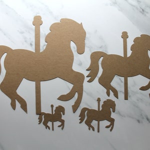 May include: Four brown cardboard cutouts of carousel horses in various sizes. The horses are all facing the right and have a simple design.