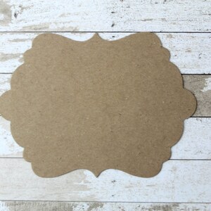 May include: A brown, blank, decorative wooden sign with a scalloped edge. The sign is made of wood and has a rustic look.