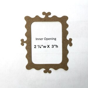 May include: A brown cardboard picture frame with a scalloped edge and a decorative design at the top and bottom. The frame has an inner opening of 2 1/4" wide by 3" high.
