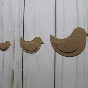 May include: Three brown wooden bird cutouts of different sizes. The birds are layered to create a 3D effect.