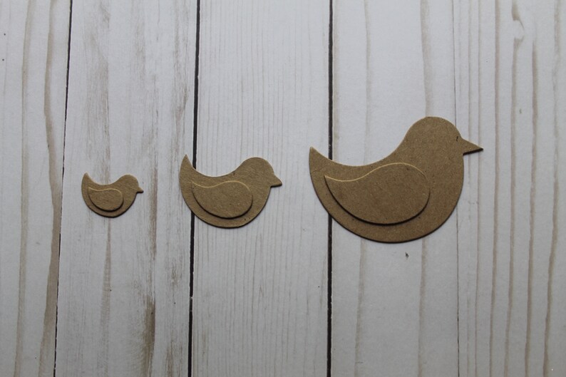 May include: Three brown wooden bird cutouts of different sizes. The birds are layered to create a 3D effect.