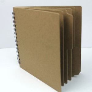 May include: A brown cardboard spiral bound notebook with multiple dividers. The notebook is closed and the spine is visible.