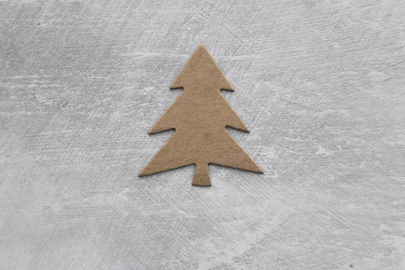 May include: A simple brown cardboard cutout of a Christmas tree on a gray textured background.