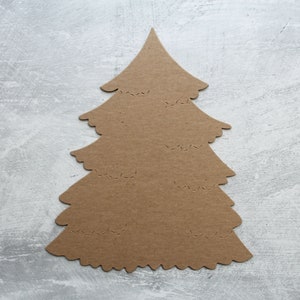May include: A brown cardboard cutout of a Christmas tree with a scalloped edge. The tree is decorated with small holes.