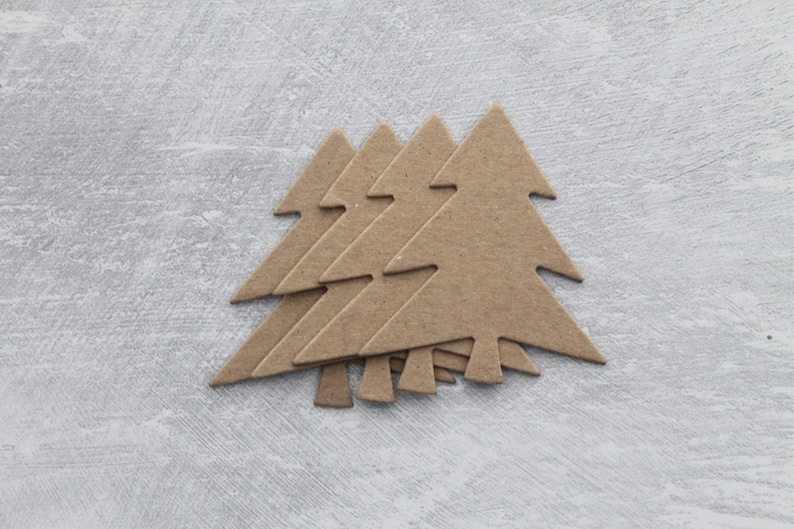May include: Five brown cardboard Christmas tree shapes stacked on top of each other against a light gray background.
