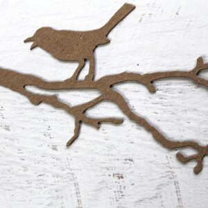 May include: A brown paper silhouette of a bird perched on a branch with leaves.