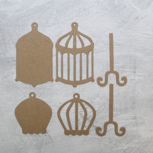 May include: Five brown paper cutouts of birdcages and stands. Two of the birdcages are solid, while the other three have a cut-out design. One of the stands has a cut-out design.